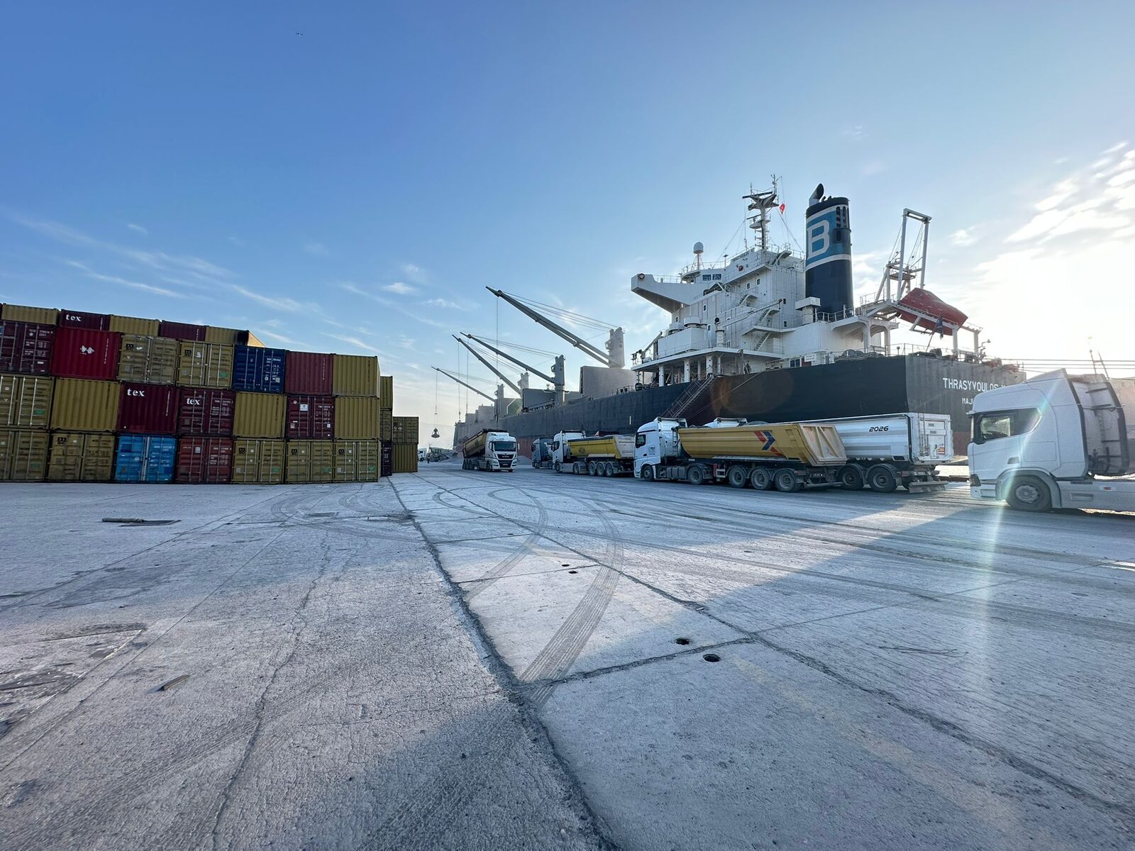 Bulk carrier alongside with tanker trucks staged for cargo operations